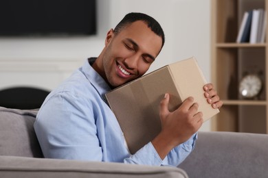 Photo of Happy young man with parcel at home. Internet shopping