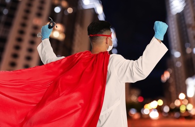 Image of Doctor dressed as superhero on night city background. Medical workers fighting with dangerous diseases