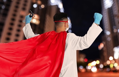 Doctor dressed as superhero on night city background. Medical workers fighting with dangerous diseases