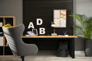 Photo of Comfortable workplace with wooden table and armchair