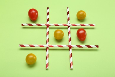 Tic tac toe game made with cherry tomatoes on light green background