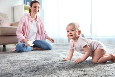 Photo of Adorable little baby crawling near mother at home