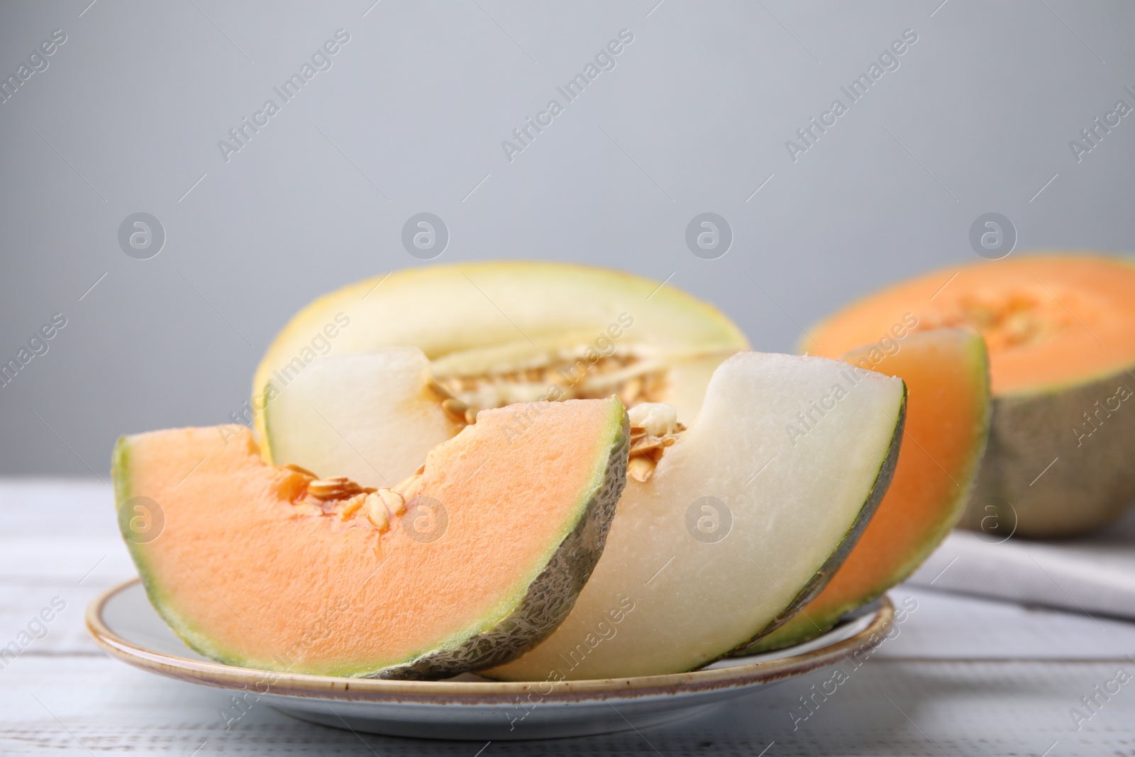 Photo of Tasty colorful ripe melons on white wooden table, closeup