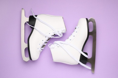 Photo of Pair of skates on violet background, flat lay