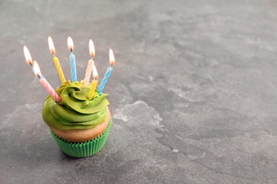Photo of Delicious birthday cupcake with burning candles on table