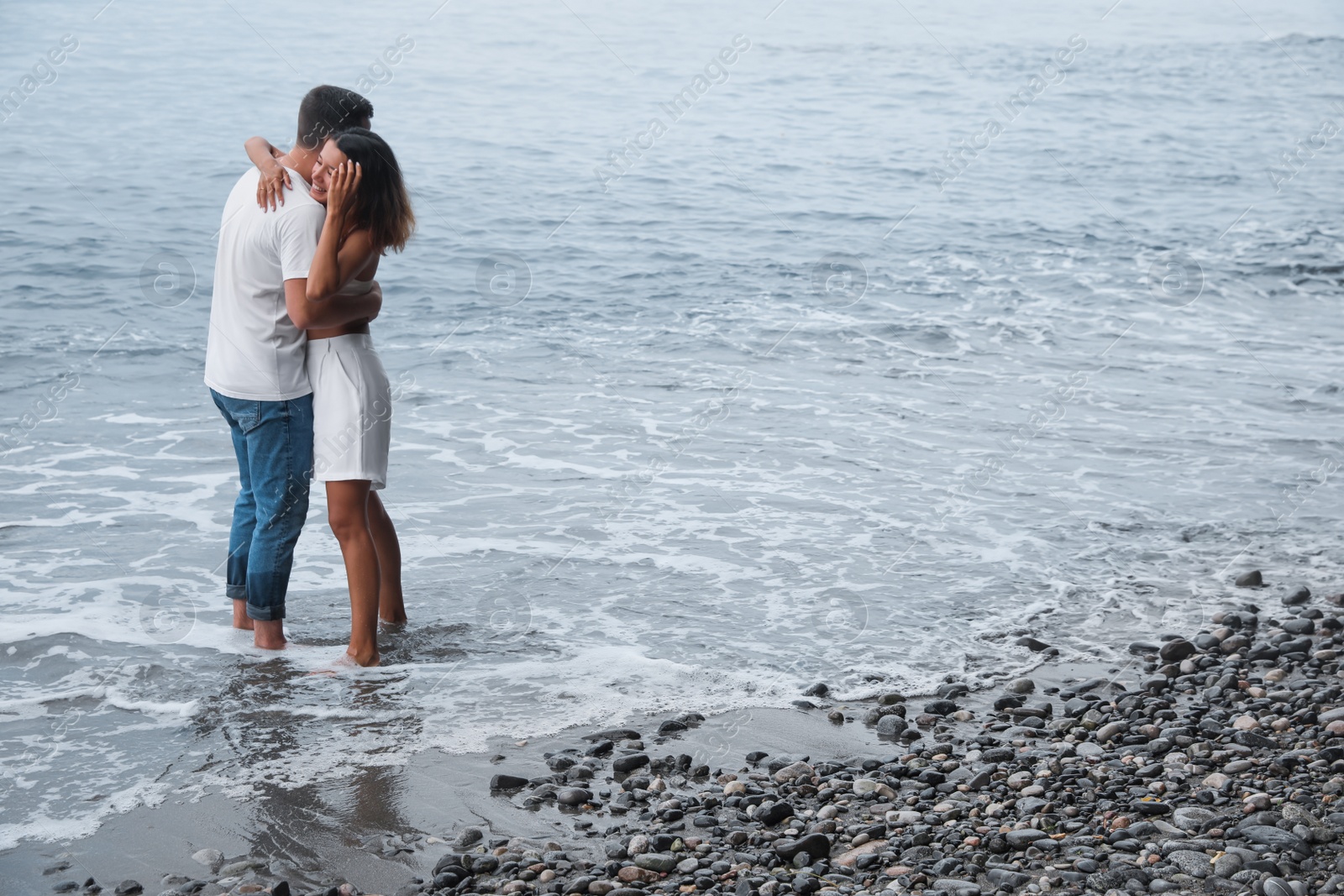 Photo of Happy young couple on beach near sea. Space for text