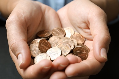 Young woman holding coins on black background, closeup view