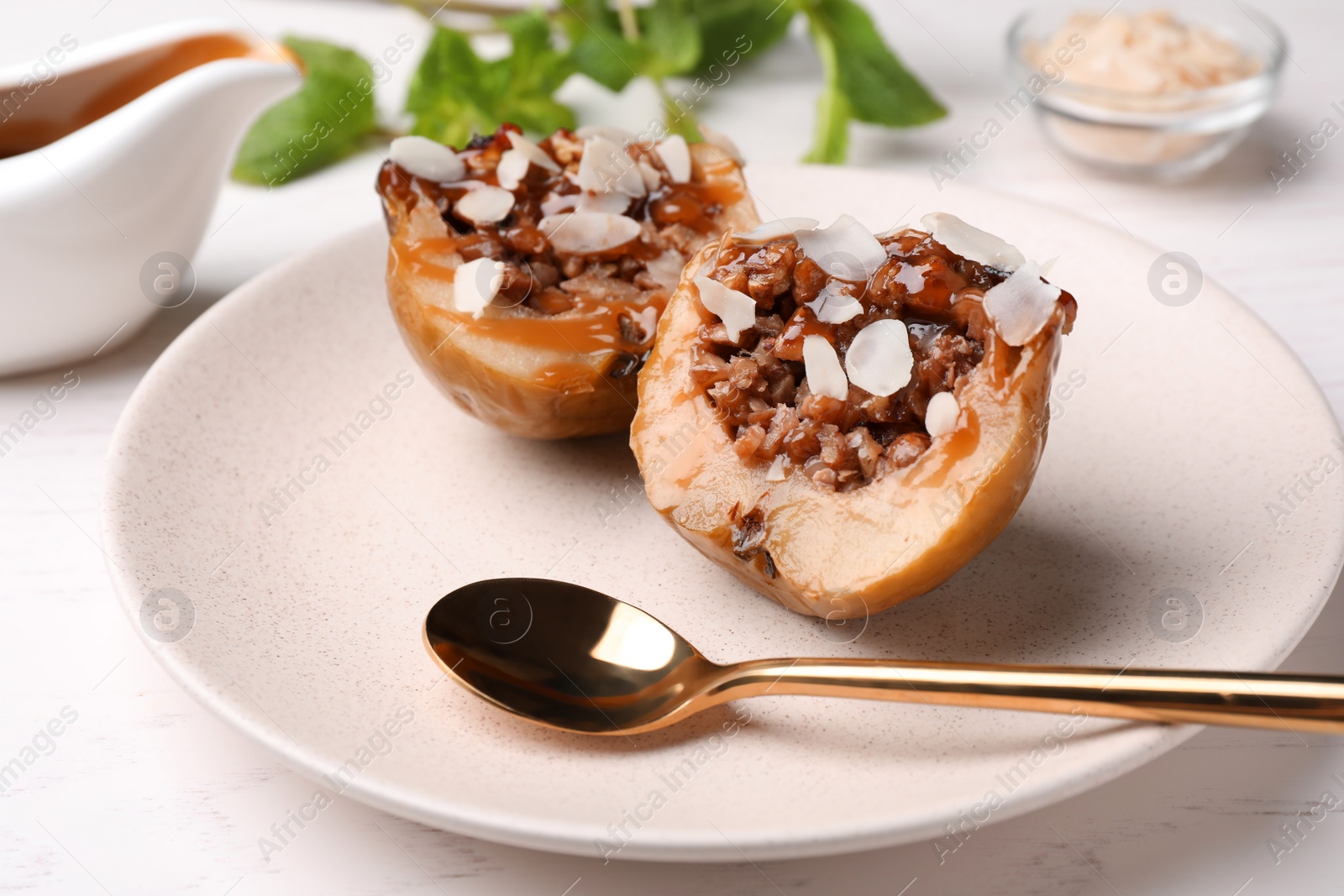 Photo of Delicious baked apple halves with nuts and caramel served on white table