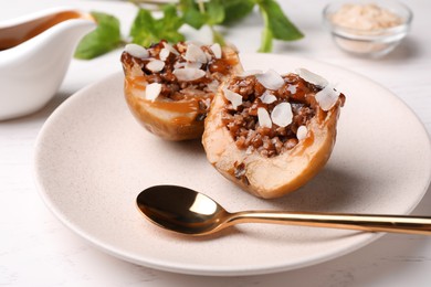 Photo of Delicious baked apple halves with nuts and caramel served on white table