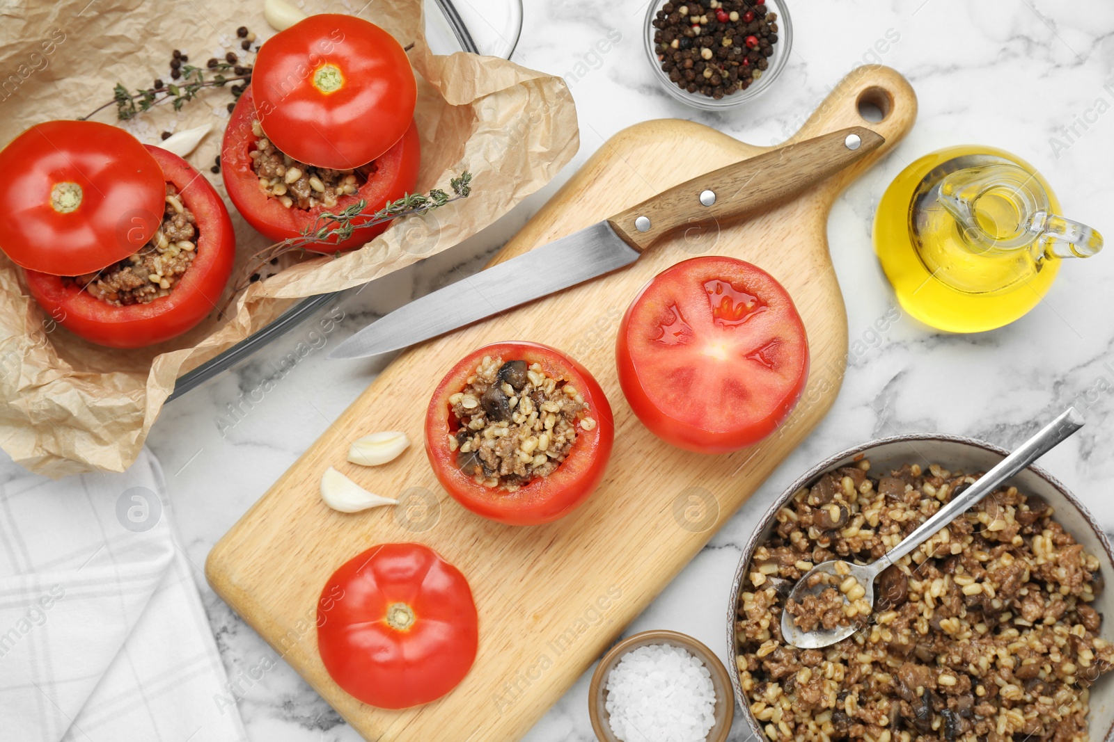 Photo of Preparing stuffed tomatoes with minced beef, bulgur and mushrooms on white marble table, flat lay