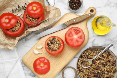 Photo of Preparing stuffed tomatoes with minced beef, bulgur and mushrooms on white marble table, flat lay