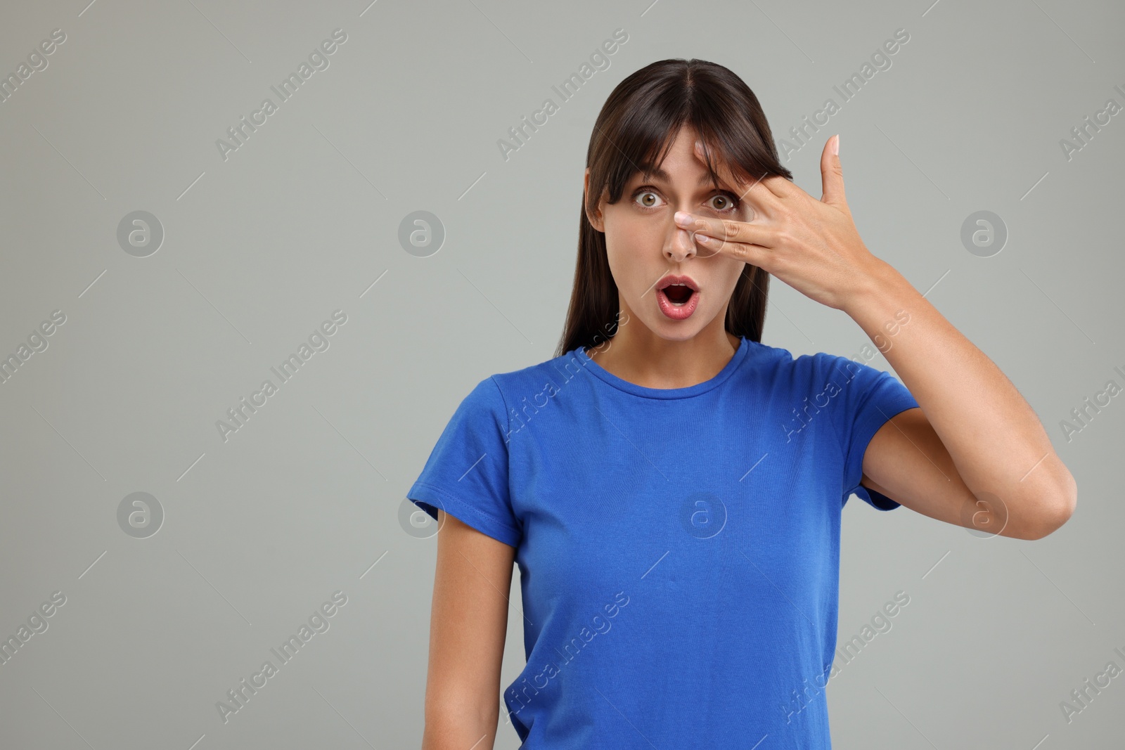 Photo of Embarrassed woman covering face on light grey background, space for text