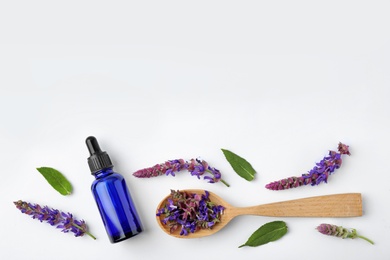 Composition with bottle of sage essential oil and flowers on white background, top view