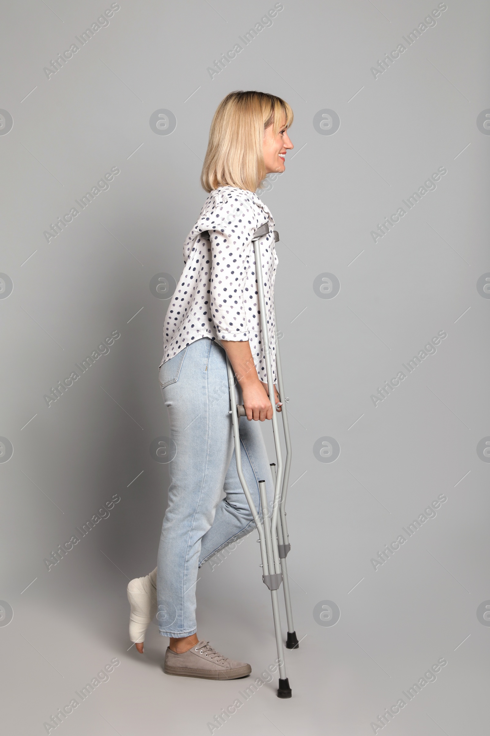 Photo of Full length portrait of woman with crutches on grey background