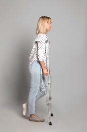 Photo of Full length portrait of woman with crutches on grey background