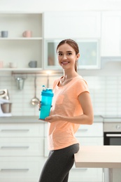 Photo of Athletic young woman with protein shake in kitchen