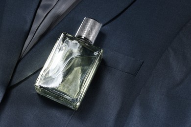 Photo of Luxury men's perfume in bottle on grey jacket, space for text