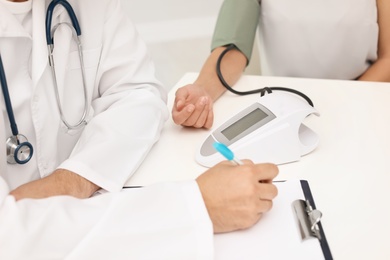 Doctor checking patient's blood pressure in hospital