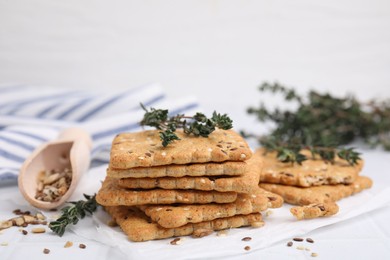 Photo of Cereal crackers with flax, sesame seeds and thyme on white tiled table, closeup