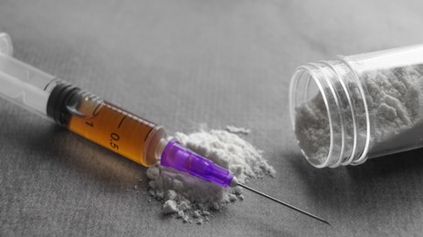 Plastic container with powder and syringe on grey table, closeup. Hard drugs