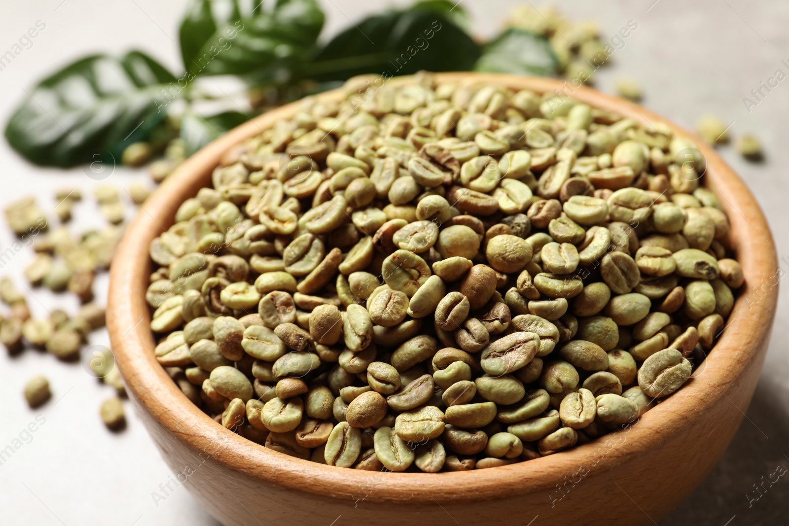 Photo of Green coffee beans in wooden bowl on table, closeup