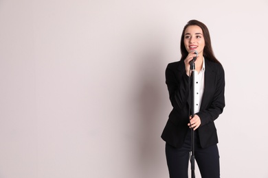 Young businesswoman with microphone on color background. Space for text