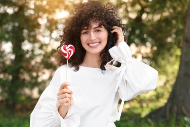 Photo of Beautiful woman in white blouse with lollipop outdoors