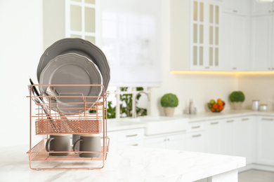 Photo of Drying rack with clean dishes on table in kitchen. Space for text