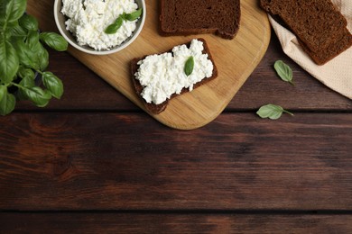 Bread with cottage cheese and basil on wooden table, flat lay. Space for text