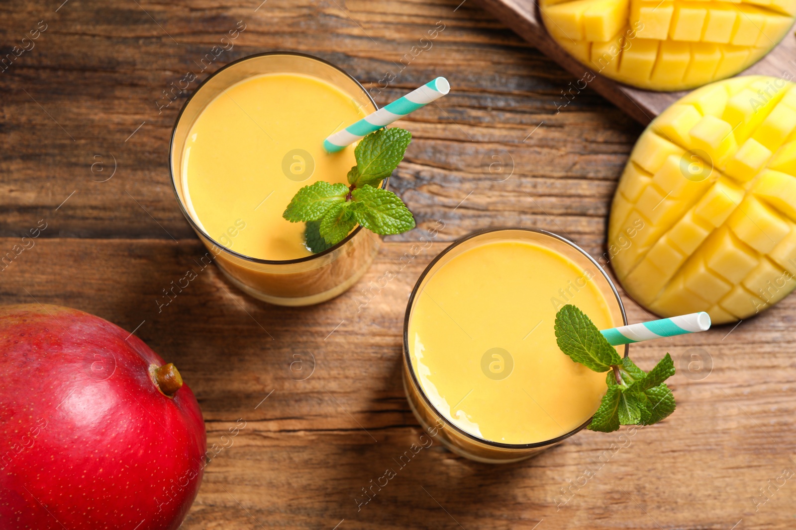 Photo of Fresh delicious mango drink on wooden table, flat lay