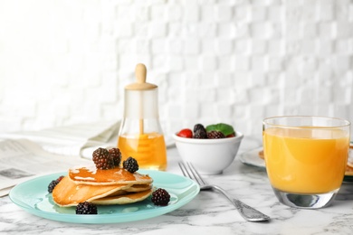 Photo of Delicious pancakes with berries, honey and glass of juice served for breakfast on table