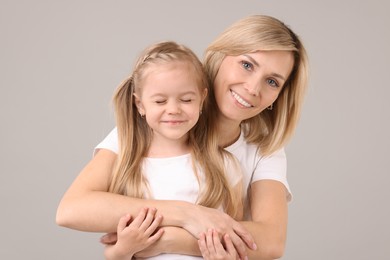 Photo of Happy mother and daughter hugging on grey background