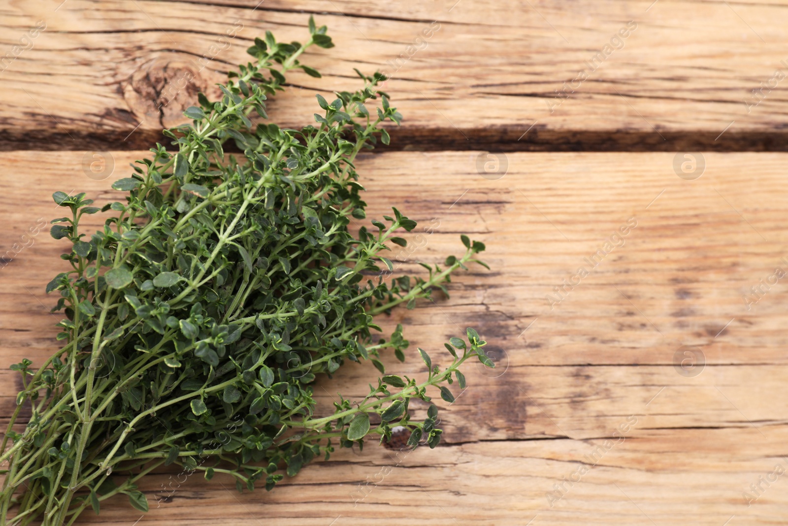 Photo of Bunch of aromatic thyme on wooden table, top view. Space for text