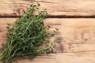 Bunch of aromatic thyme on wooden table, top view. Space for text