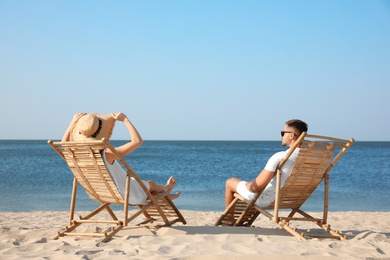 Young couple relaxing in deck chairs on beach