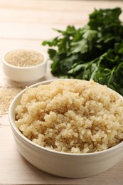 Tasty quinoa porridge in bowl on light wooden table, closeup