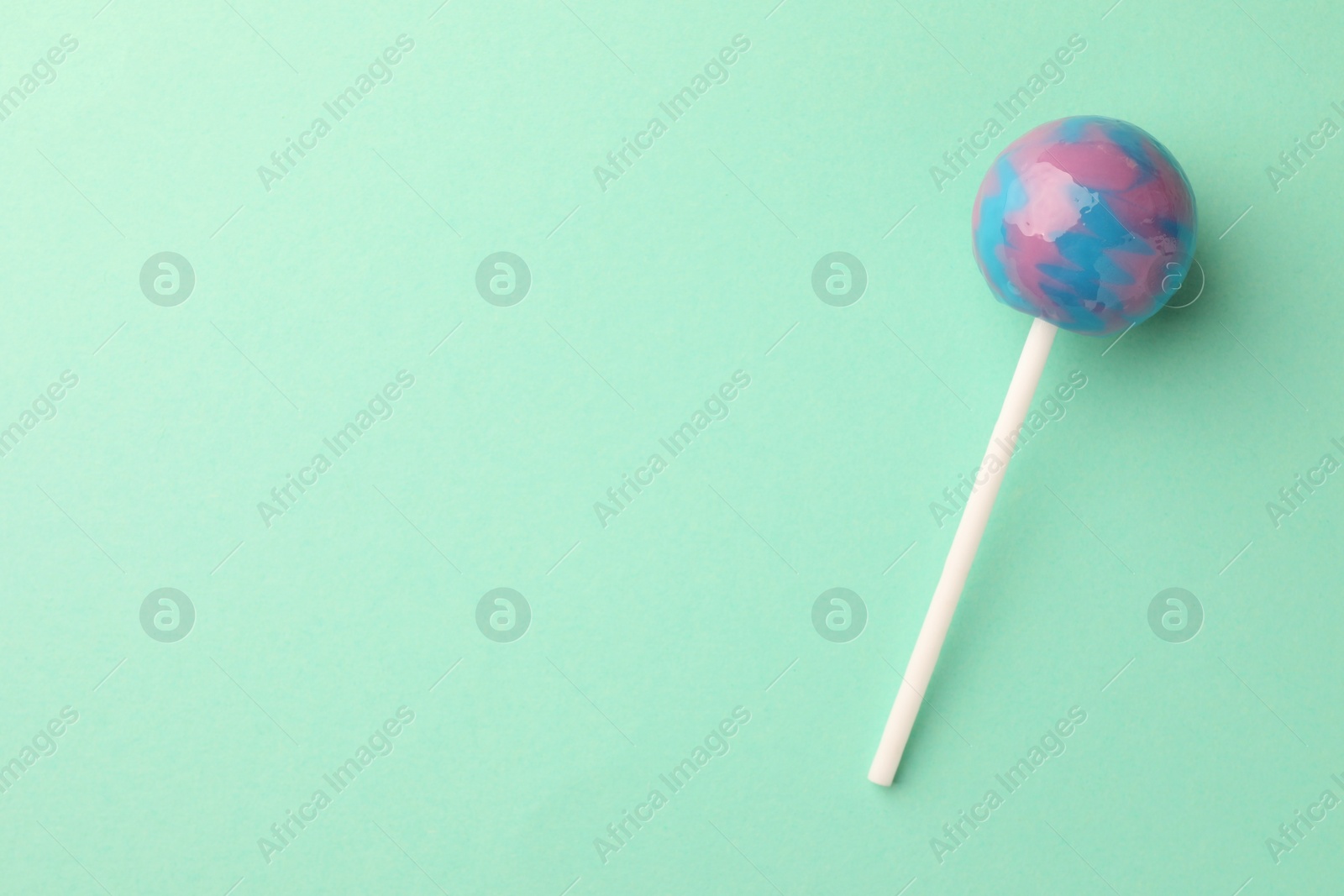 Photo of Tasty lollipop on turquoise background, top view. Space for text