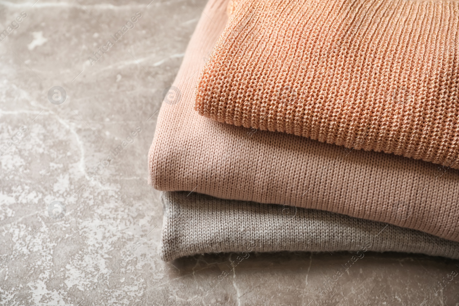 Photo of Stack of warm knitted clothes on grey background