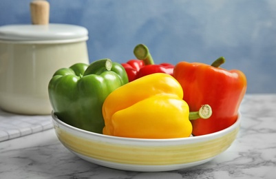 Bowl with ripe paprika peppers on table