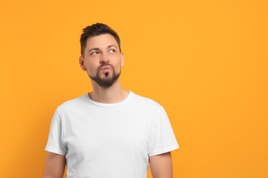 Photo of Handsome man blowing kiss on orange background. Space for text