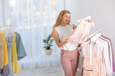 Photo of Young woman choosing stylish clothes in boutique