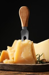 Photo of Delicious parmesan cheese with rosemary on wooden table