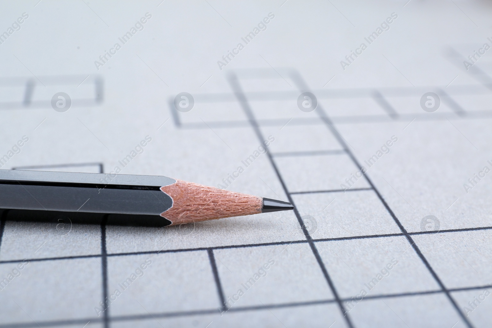 Photo of Pencil on blank crossword, closeup view. Space for text