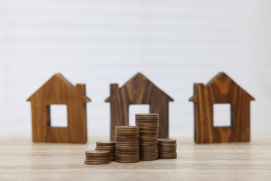 House models and stacked coins on wooden table