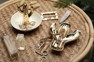 Photo of Stylish golden bijouterie and perfume on wicker table
