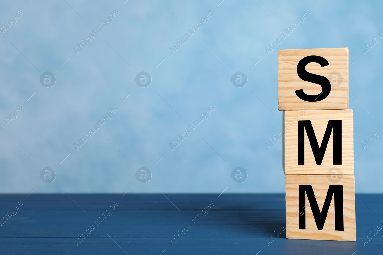 Photo of Cubes with abbreviation SMM (Social media marketing) on blue table. Space for text
