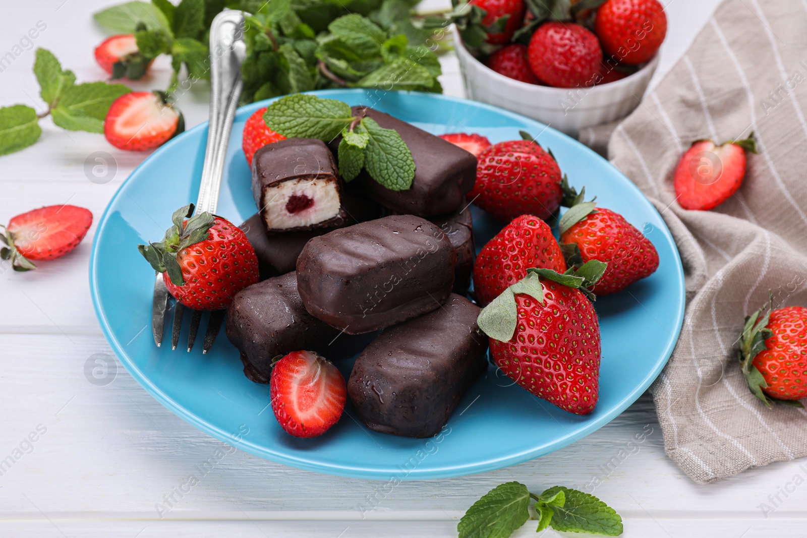 Photo of Delicious glazed curd snacks and fresh strawberries on white wooden table