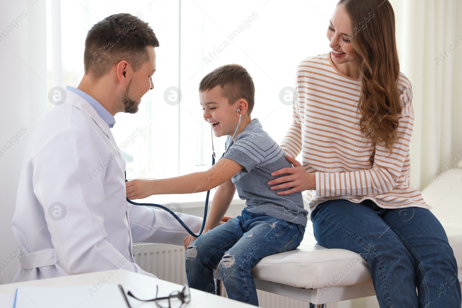 Photo of Mother and son visiting pediatrician. Doctor working with patient in hospital