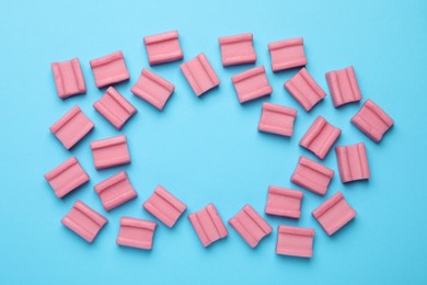 Photo of Tasty pink chewing gums on light blue background, flat lay. Space for text