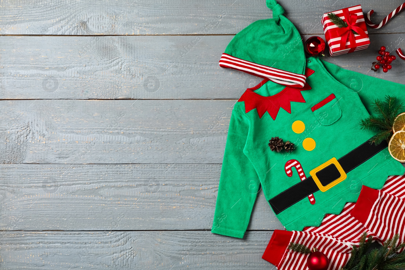 Photo of Flat lay composition with cute Christmas baby clothes on grey wooden background. Space for text